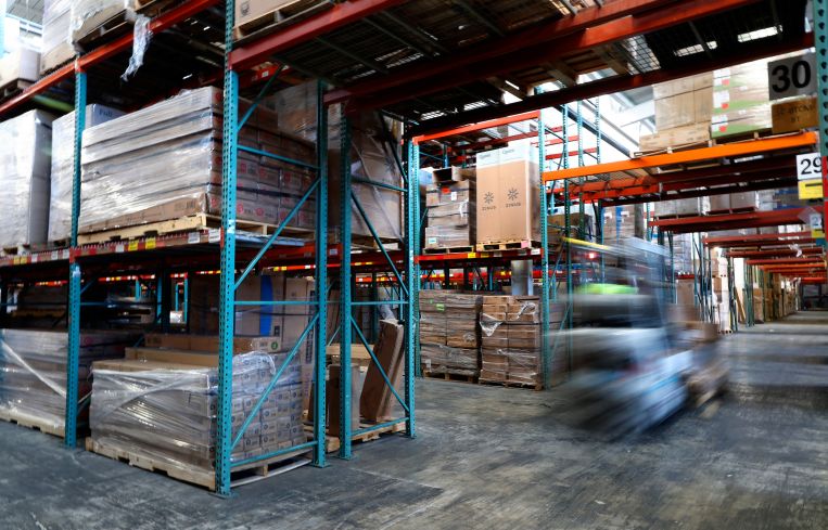 Workers on forklifts move inventory.