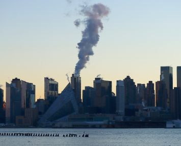 An emission comes out of a smokestack on the west side of Manhattan as the sun rises in New York City on January 16, 2022, as seen from Weehawken, New Jersey.