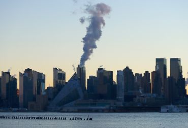 An emission comes out of a smokestack on the west side of Manhattan as the sun rises in New York City on January 16, 2022, as seen from Weehawken, New Jersey. 