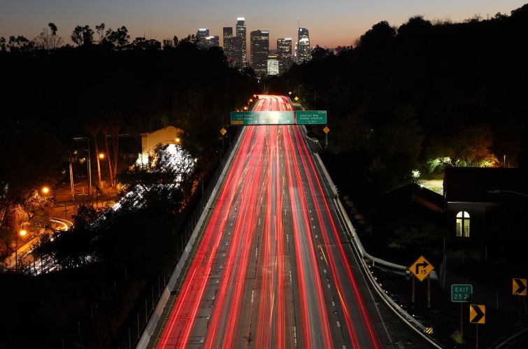 Vehicle lights are blurred in a long exposure as they make their way along the 110 freeway at dusk in Los Angeles, California.