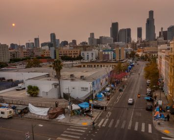 An aerial view of homeless encampments in Skid Row as smoke from California wildfires obscures the setting sun and skyline in 2021.