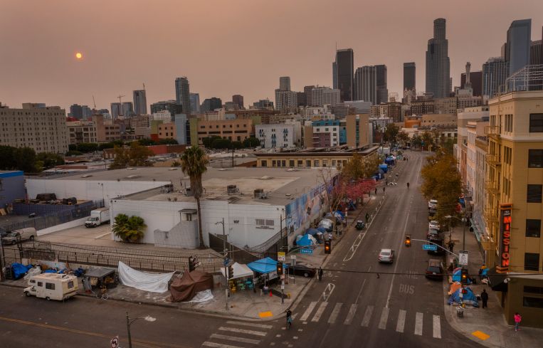 An aerial view of homeless encampments in Skid Row as smoke from California wildfires obscures the setting sun and skyline in 2021.