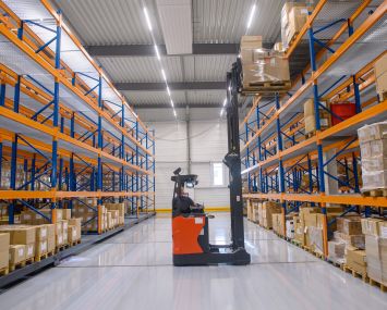 A forklift works between high racks in a clothing service center.