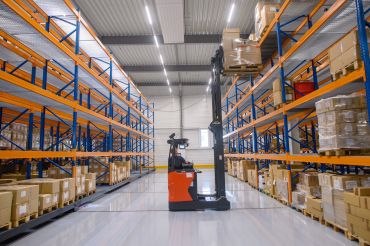 A forklift works between high racks in a clothing service center.