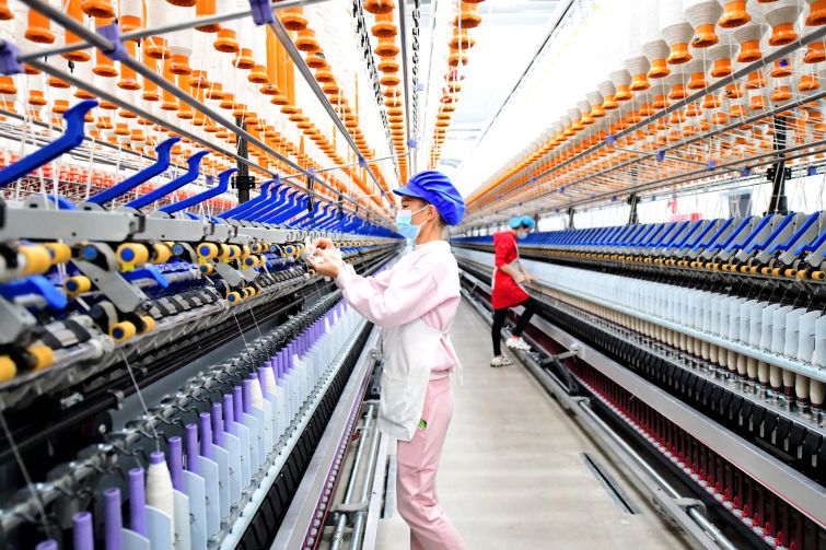 An employee operates a spinning machine at a textile factory in December.