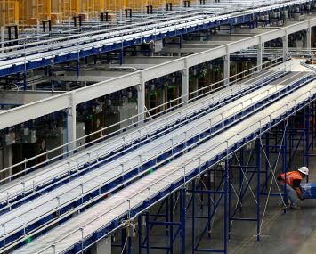 Workers construct a small section of a massive storage and conveyor system inside a warehouse leased to Skechers.