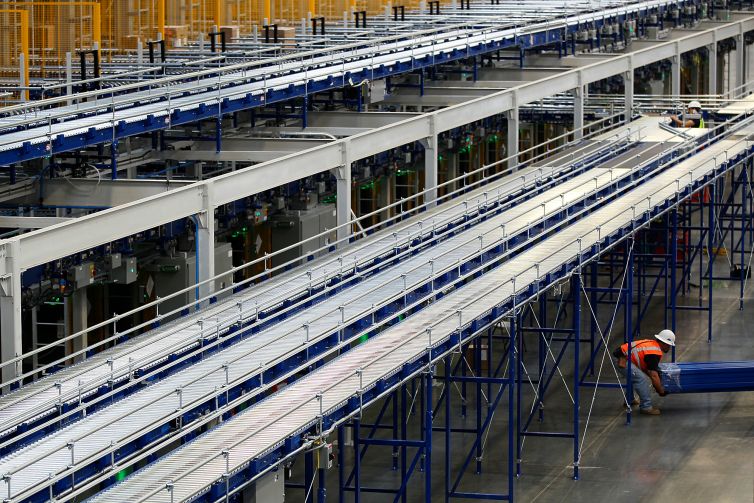 Workers construct a small section of a massive storage and conveyor system inside a warehouse leased to Skechers.