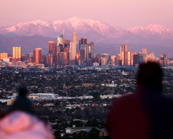 People look toward the downtown skyline, with the snow-capped San Gabriel Mountains visible beyond, on January 31, 2023 in Los Angeles, California.