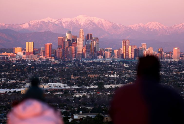 People look toward the downtown skyline, with the snow-capped San Gabriel Mountains visible beyond, on January 31, 2023 in Los Angeles, California.