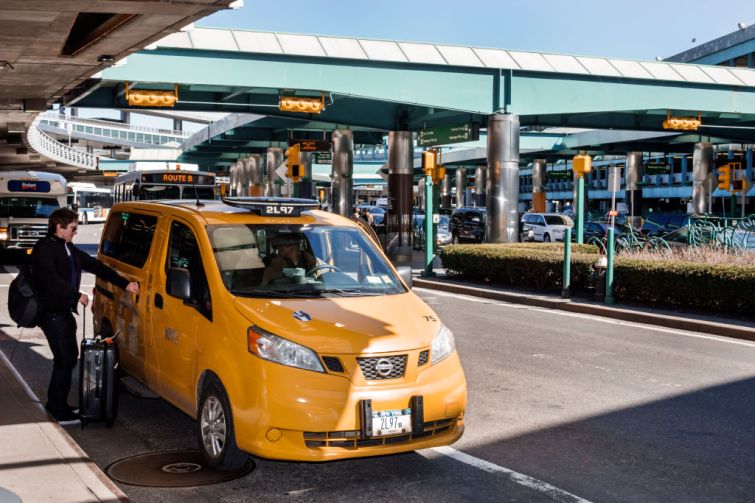 A taxi picking up a passenger outside LaGuardia Airport.