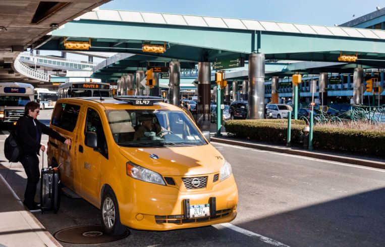 A taxi picking up a passenger outside LaGuardia Airport.