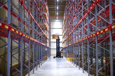 A forklift truck lifts goods into a storage rack in a warehouse of a logistics company.
