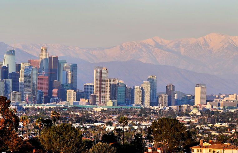 Snow-capped mountains behind the downtown skyline on March 2, 2023 in Los Angeles.