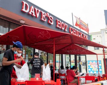 People wearing masks stand outside "Dave's Hot Chicken" near Melrose Avenue amid the pandemic on April 22, 2021 in Los Angeles, Calif.