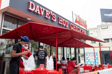 People wearing masks stand outside "Dave's Hot Chicken" near Melrose Avenue amid the pandemic on April 22, 2021 in Los Angeles, Calif.