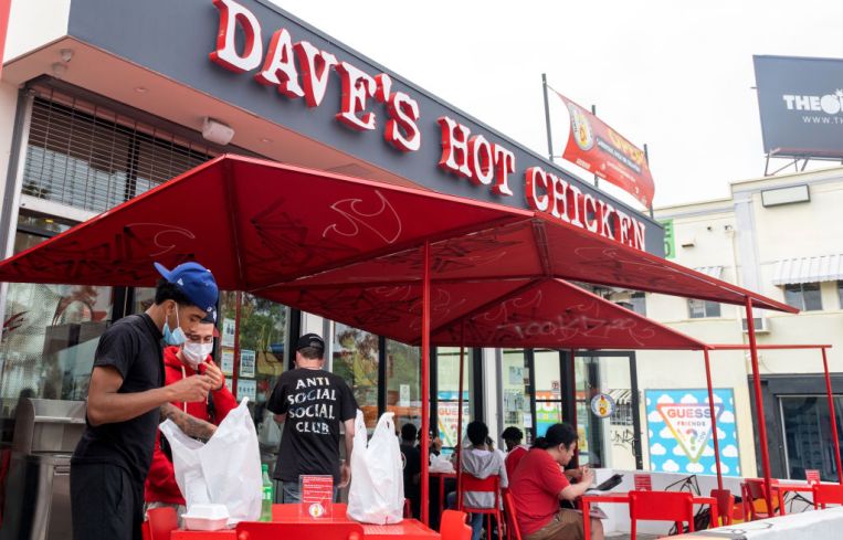 People wearing masks stand outside "Dave's Hot Chicken" near Melrose Avenue amid the pandemic on April 22, 2021 in Los Angeles, Calif.