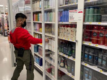 Target employee stocking personal hygiene items in new locked security shelving, Target, Queens, New York.