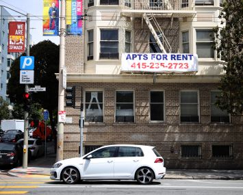 A "for rent" sign posted on the exterior of an apartment building.