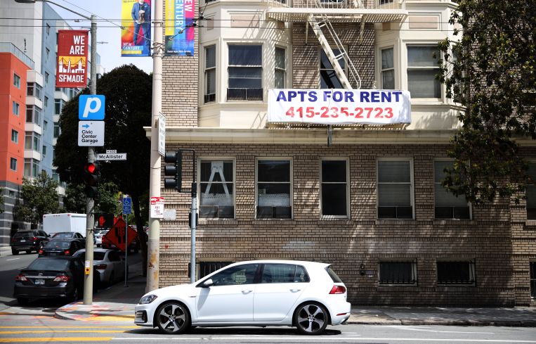 A "for rent" sign posted on the exterior of an apartment building.