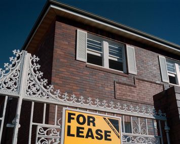 A "for lease" sign sits in front of an apartment building.