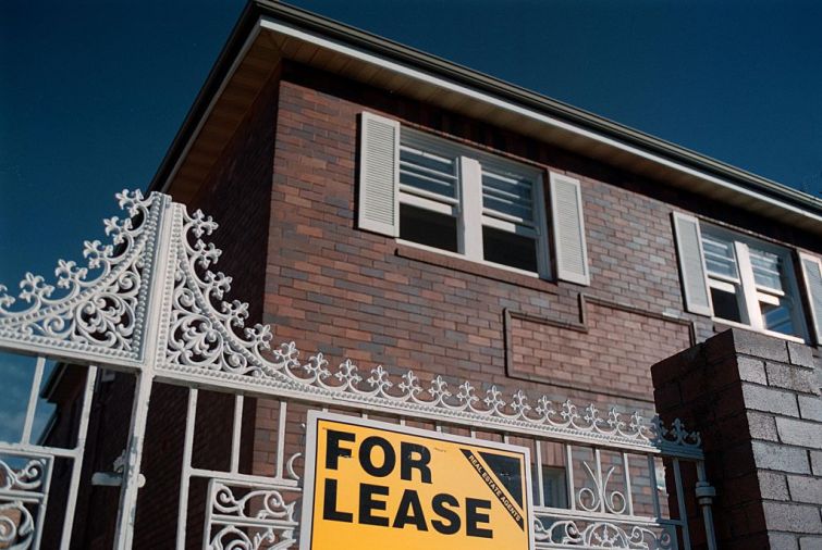 A "for lease" sign sits in front of an apartment building.