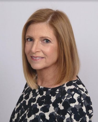 A woman's head turning to the camera and smiling.