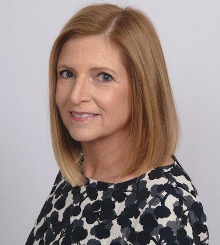 A woman's head turning to the camera and smiling.