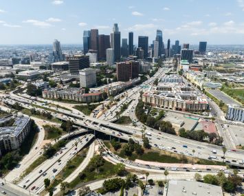 Los Angeles skyline and the four-level interchange where the 110 and 101 freeways meet in the summer 2023.