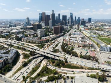 Los Angeles skyline and the four-level interchange where the 110 and 101 freeways meet in the summer 2023.