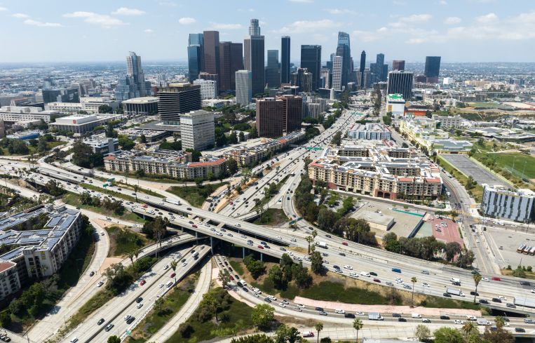 Los Angeles skyline and the four-level interchange where the 110 and 101 freeways meet in the summer 2023.