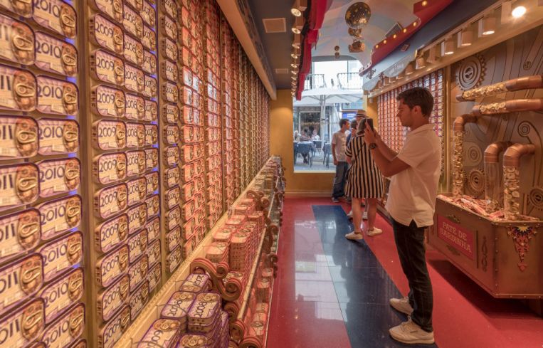 A man taking a photo of sardine cans in a store.