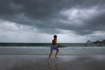 Storm clouds hang over people as they enjoy the beach before the possible arrival of Hurricane Idalia in Clearwater Beach. 