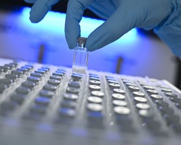 Biology lab technician Julia Volk removes a freeze-dried sample from a container in a laboratory.