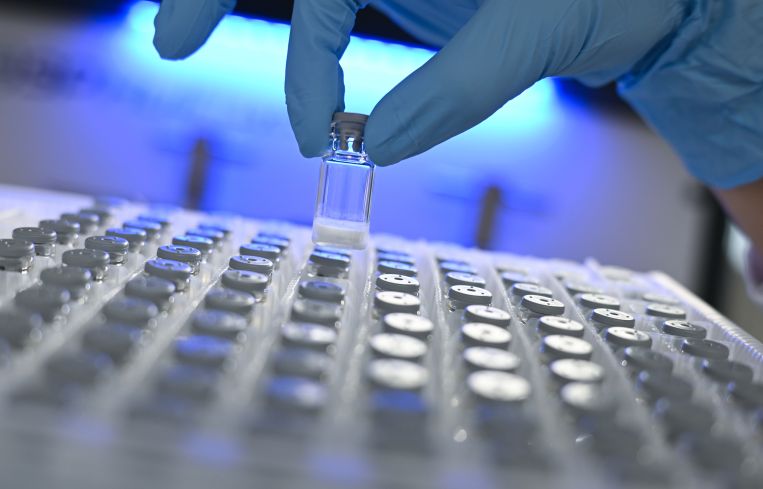 Biology lab technician Julia Volk removes a freeze-dried sample from a container in a laboratory.