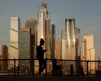 The sun sets on the Empire State Building and the towers of Hudson Yards in New York City.