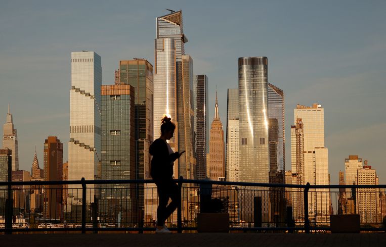 The sun sets on the Empire State Building and the towers of Hudson Yards in New York City.