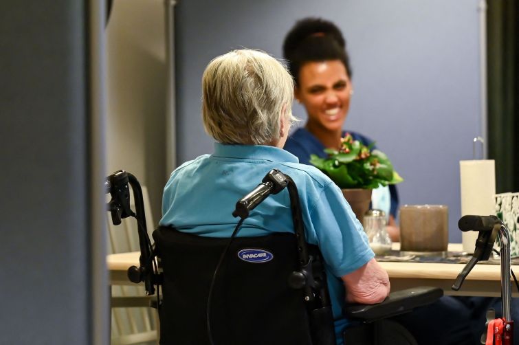 An employee speaking to an elderly woman at a retirement home.