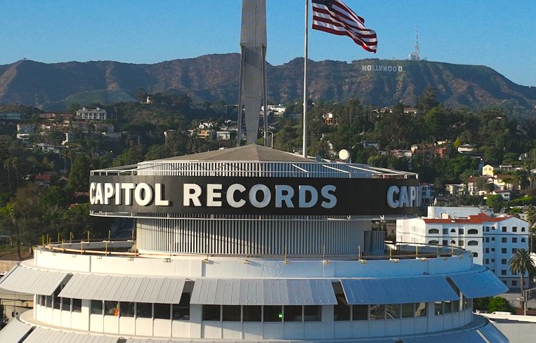 Aerial drone view of the iconic Capitol Records Building and the Hollywood sign.
