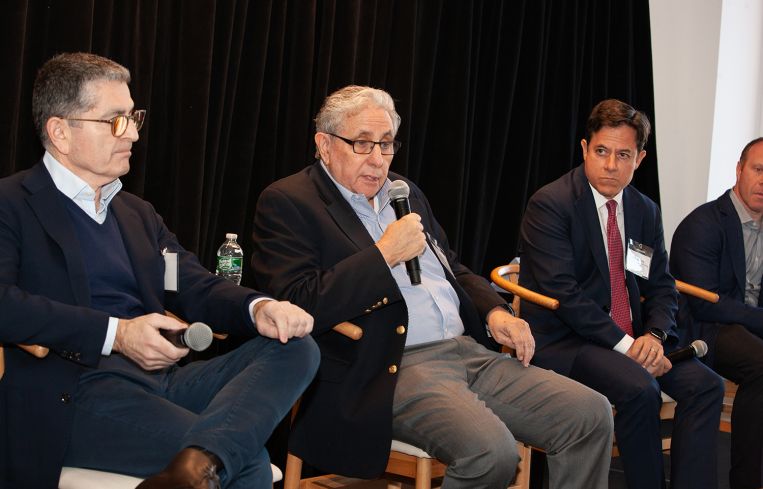 Four men seated on a stage.