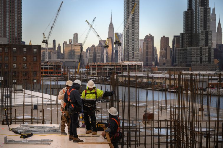 Four construction workers talk to each other with the Manhattan skyline in the background.
