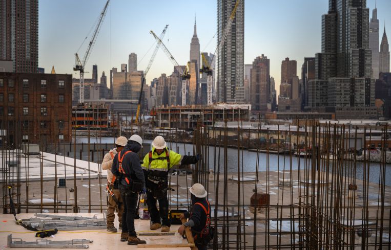 Four construction workers talk to each other with the Manhattan skyline in the background.