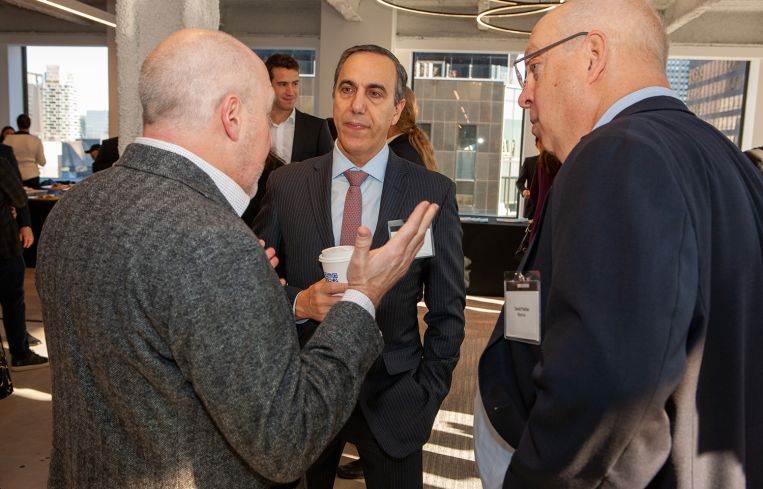 Three men in suits talking to each other.