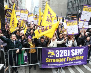 Union members wave yellow and purple signs behind a police barricade in Manhattan.