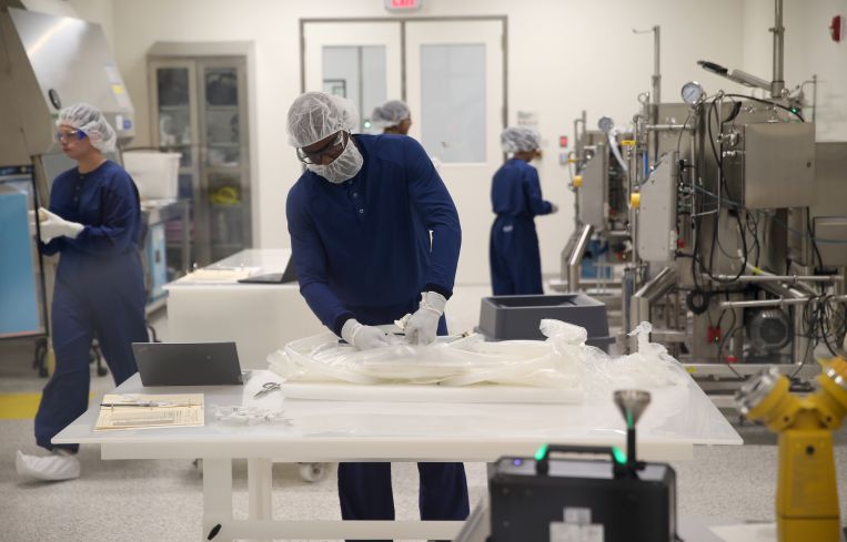 Some of the workers inside the new Ultragenyx biomanufacturing facility. They are in a solution prep-room for manufacturing.