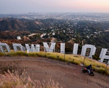 A cyclist passes above the Hollywood sign shortly after sunset in Los Angeles.