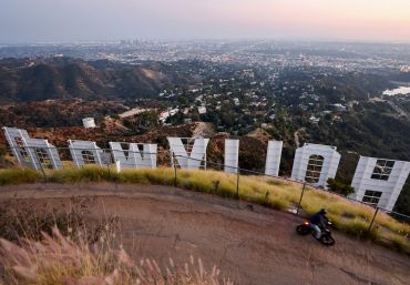 A cyclist passes above the Hollywood sign shortly after sunset in Los Angeles.
