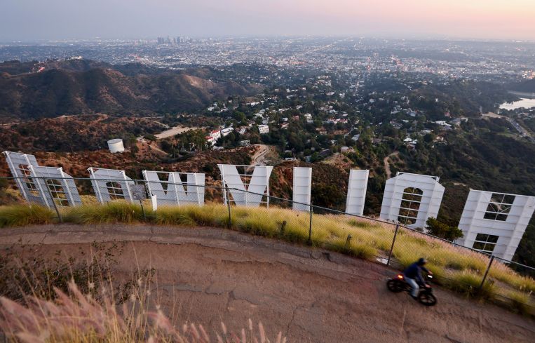 A cyclist passes above the Hollywood sign shortly after sunset in Los Angeles.