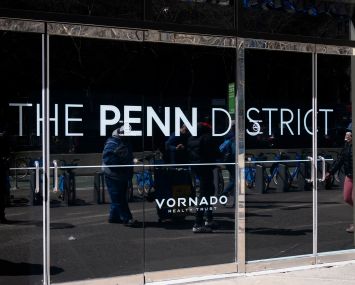 Pedestrians are reflected in the windows of one of Vornado's Penn District buildings.
