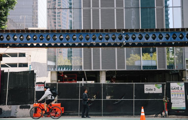 People pass a building where construction is underway for apartments in Downtown L.A.