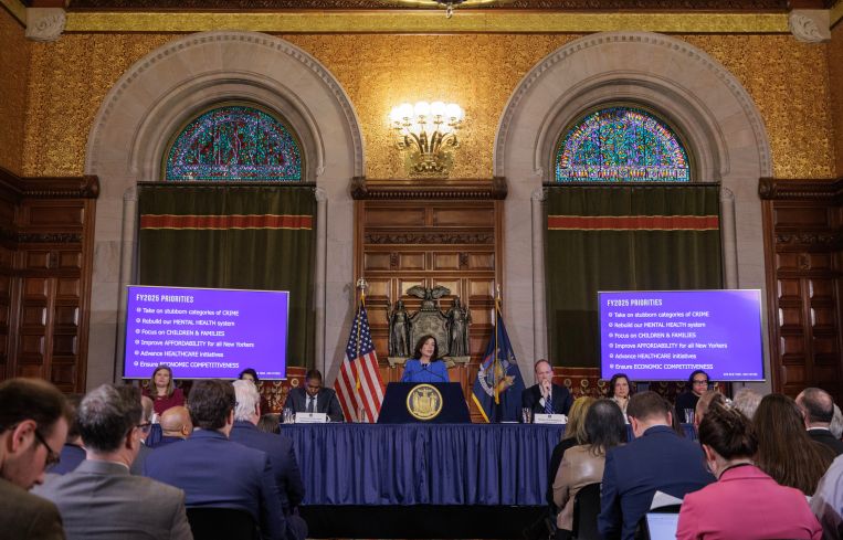The governor stands at a podium in the Red Room at the state capitol.